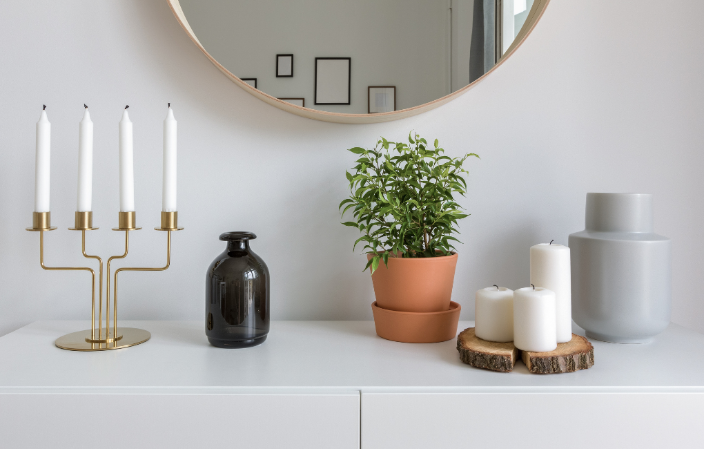 Ein Bild mit verschiedenen Accessoires wie Kerzen, Vase, Blumentopf und Kerzenständer